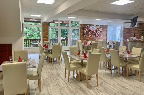 a dining room with tables and chairs and a wall of windows at Colosseum Étterem és Apartman Salgótarján in Salgótarján