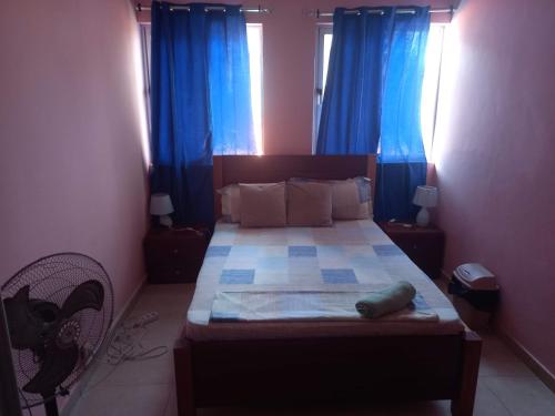 a bedroom with a large bed with blue curtains at Casa Barreto in Tarrafal
