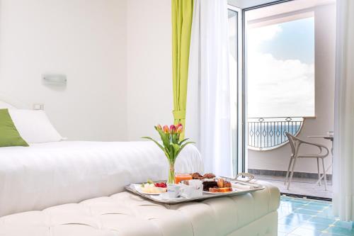 Sala de estar con sofá blanco y bandeja de comida en Hotel La Madonnina en Ischia