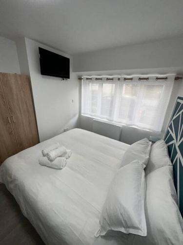 een slaapkamer met een wit bed en een tv aan de muur bij studio 2 au cœur de Périgueux in Périgueux