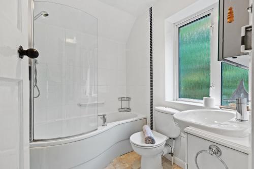 a white bathroom with a tub and a toilet and a sink at Ruby Cottage - Beachside Cottage with Views in Saundersfoot