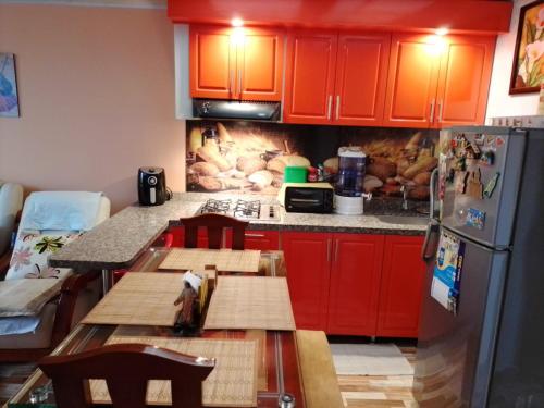 uma cozinha com armários vermelhos, uma mesa e um frigorífico em Apartamento El Rosal Cundinamarca em El Rosal