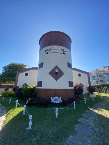 un edificio con una torre de reloj en el césped en Portal dos Anjos - Casa 03, en Arraial do Cabo