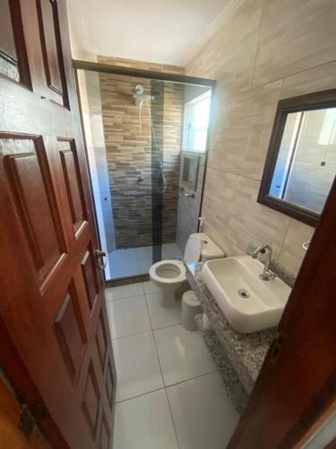 a bathroom with a toilet and a sink and a door at Portal dos Anjos - Casa 03 in Arraial do Cabo