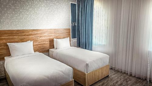 a hotel room with two beds and a window at Hotel Bankir Khiva in Khiva