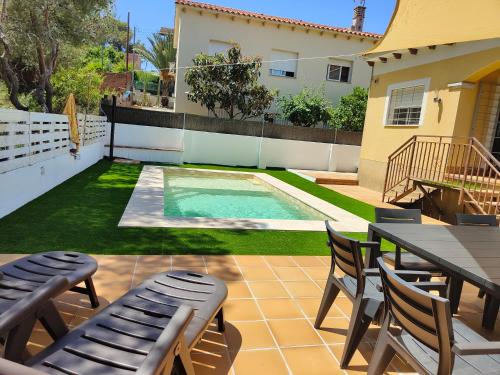 un patio con mesa y sillas y una piscina en Villa Genís, en Calafell