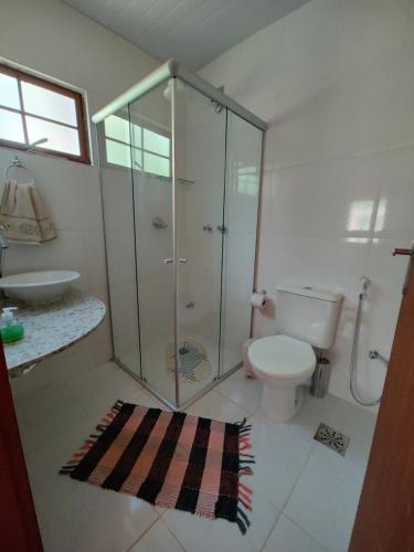uma casa de banho com um chuveiro, um WC e um lavatório. em Govinda Moeda Pousada em Moeda