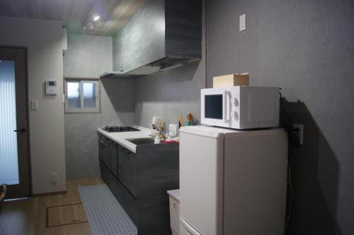 a kitchen with a microwave on top of a refrigerator at 花田屋HANADAYA in Nishinotōindōri
