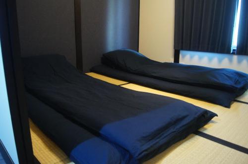 twee bedden in een kamer met blauwe lakens bij 花田屋HANADAYA in Nishinotōindōri