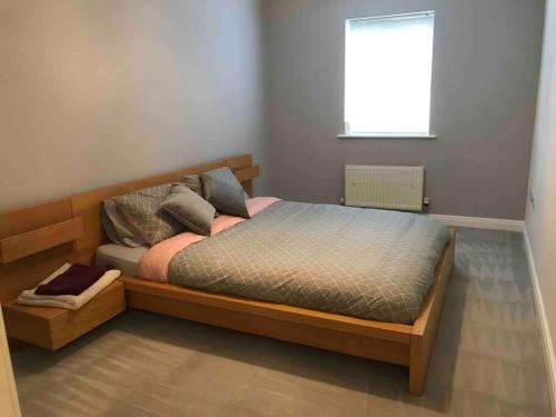 um quarto com uma cama de madeira e uma janela em Stylish, Bright & Spacious 2 Bed Apartment with Parking, Fulwood, Preston em Grimsargh
