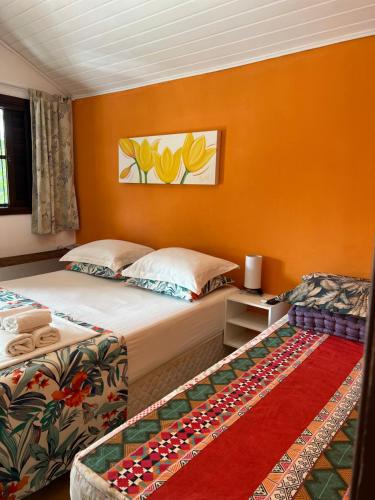 a bedroom with two beds and an orange wall at Suites Helena in Ilhabela