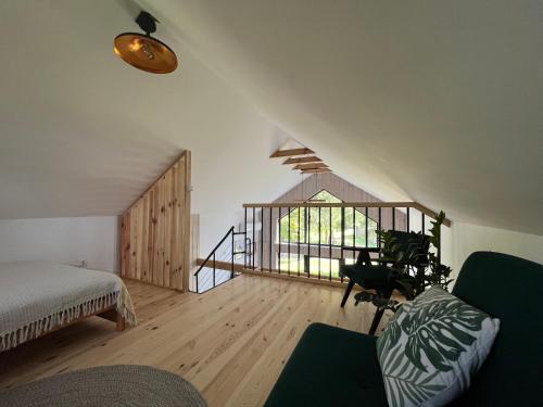 a attic room with a bed and a window and a couch at Trzy Stodoły - Kraina Łąk domki całoroczne na Roztoczu in Narol