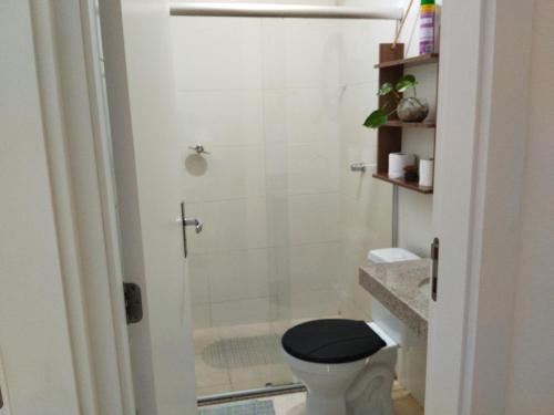 W łazience znajduje się prysznic oraz toaleta z czarnym fotelem. w obiekcie Apto Aconchegante na Praia Coroa Vermelha w mieście Santa Cruz Cabrália