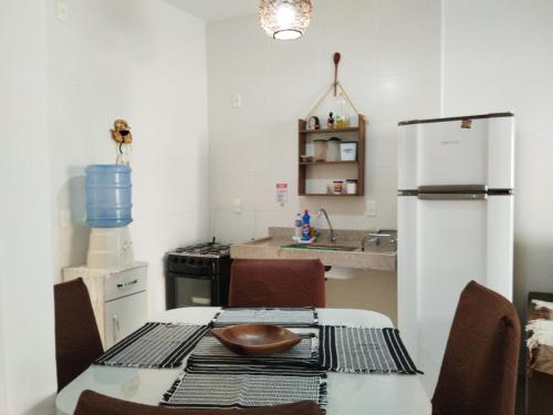 uma cozinha com uma mesa e um frigorífico branco em Apto Aconchegante na Praia Coroa Vermelha em Santa Cruz Cabrália