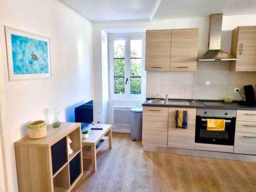 a kitchen with white walls and wooden cabinets at Le St Apollinaire n°2-Ma Cabotte in Meximieux
