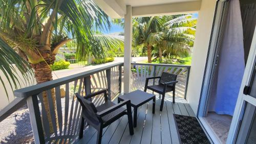a balcony with two chairs and a table and a palm tree at Studio Varia in Rarotonga