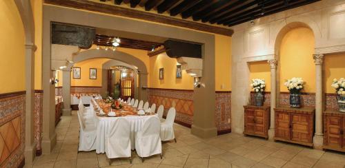 a banquet hall with a long table with white chairs at Hotel Posada Santa Fe in Guanajuato