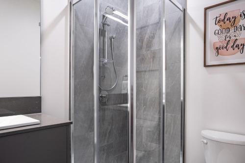 a shower with a glass door in a bathroom at Rummy's Adventure Bay by Revelstoke Vacations in Revelstoke