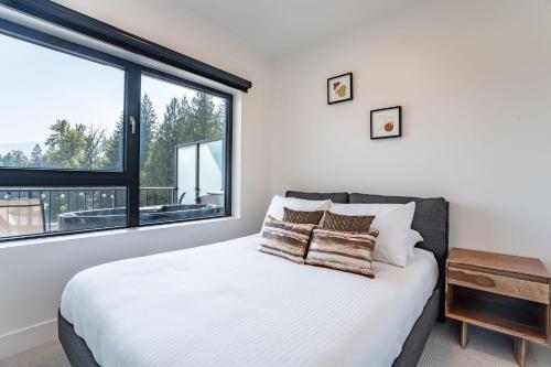 a bedroom with a bed and a large window at Rummy's Adventure Bay by Revelstoke Vacations in Revelstoke