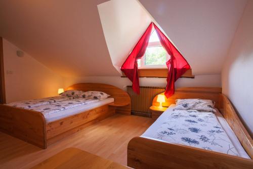 um quarto no sótão com 2 camas e uma janela em Domačija Malnarjevi em Villa Slavina