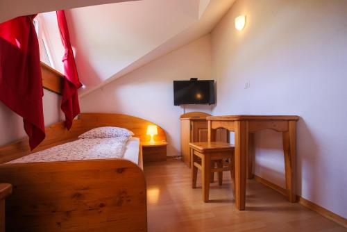 a bedroom with a bed and a desk with a tv at Domačija Malnarjevi in Villa Slavina
