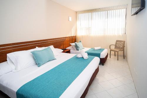 a hotel room with two beds and a chair at Hotel Portobelo Convention Center in San Andrés