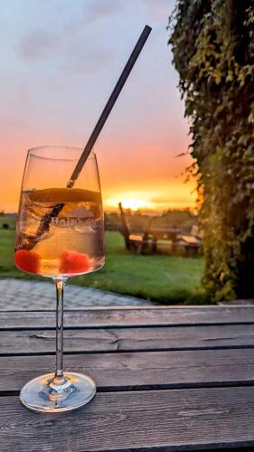 a glass of wine sitting on a table with the sunset at Hainberg Hotel Garni in Habrachćicy