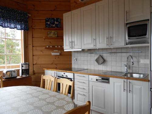 a kitchen with white cabinets and a table with chairs at Tornvillan in Hammarland