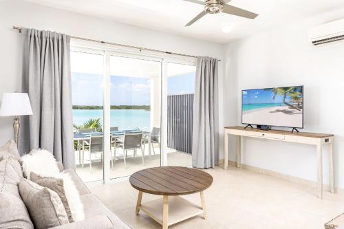 a living room with a couch and a tv at NEW Tropical Waterfront Cooper Jack Bay Villas in Five Cays Settlement