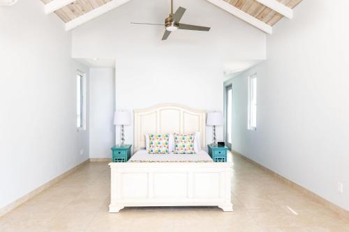 a white bedroom with a bed and a ceiling fan at NEW Tropical Waterfront Cooper Jack Bay Villas in Five Cays Settlement