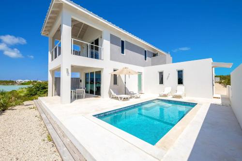 a white house with a swimming pool in front of it at NEW Tropical Waterfront Cooper Jack Bay Villas in Five Cays Settlement