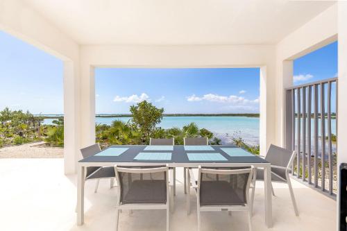 a table and chairs on a balcony with a view of the ocean at NEW Tropical Waterfront Cooper Jack Bay Villas in Five Cays Settlement