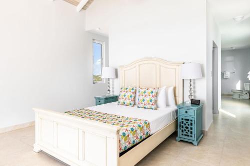 a white bedroom with a bed and a blue night stand at NEW Tropical Waterfront Cooper Jack Bay Villas in Five Cays Settlement