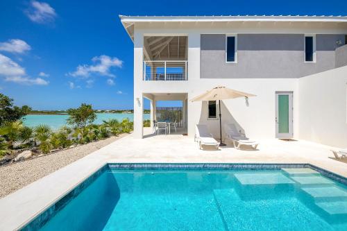 a villa with a swimming pool and a house at NEW Tropical Waterfront Cooper Jack Bay Villas in Five Cays Settlement