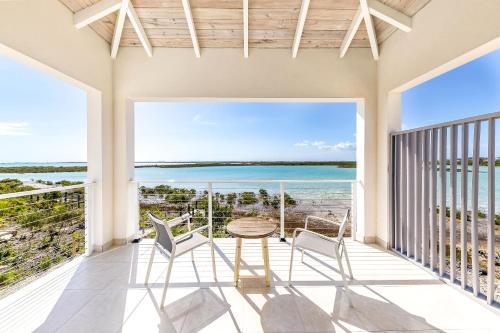 a balcony with a table and chairs and a view of the ocean at NEW Tropical Waterfront Cooper Jack Bay Villas in Five Cays Settlement