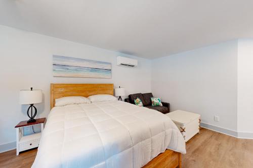 a white bedroom with a large bed and a chair at Town of Rehoboth Beach - 99 Sussex St Unit #6 in Rehoboth Beach