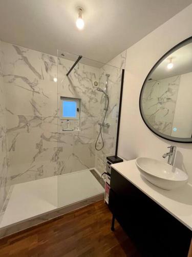 a bathroom with a sink and a shower with a mirror at Maison proche CNPE in Saint-Folquin