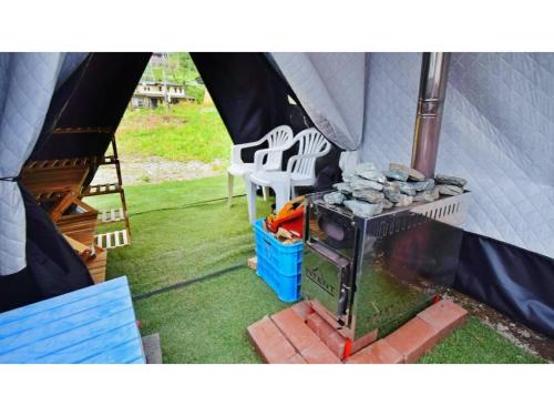 a inside of a tent with a stove and two chairs at Ashinomaki Prince Hotel - Vacation STAY 55298v in Aizuwakamatsu