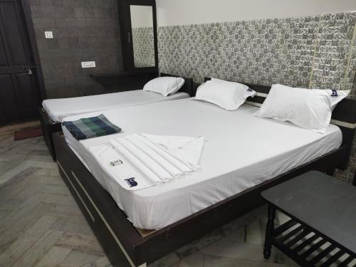 2 letti con lenzuola bianche e asciugamani di Hotel Karthikeya Residency a Kākināda