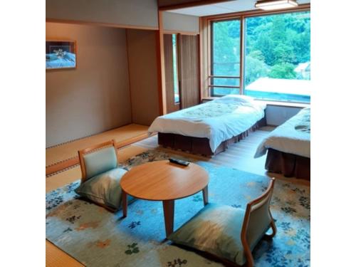雫石町にあるOshuku Onsen Choeikan - Vacation STAY 55588vのベッド2台、テーブル、椅子が備わる客室です。