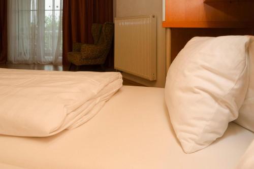 ein Bett mit weißer Bettwäsche und einem Kissen darauf in der Unterkunft Apartment in Podersdorf am See with a bicycle storage in Podersdorf am See