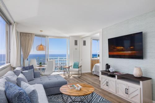 a living room with a blue couch and a tv at Ilikai Collection 12 Corner Oceanfront Condo with amazing views in Honolulu