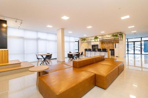 uma grande sala de estar com um sofá e mesas em CWBe Residencial em Curitiba