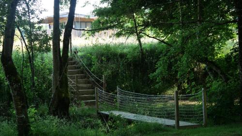 a rope bridge in the middle of a forest at Les Chalets du Moulin de Valade in Condat-sur-Trincou