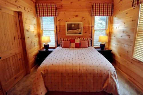 Un dormitorio con una cama en una habitación de madera. en Water's Edge ~ Covered Porch w/ Deep Creek as your Backyard Haven, en Bryson City