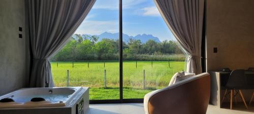 a room with a tub and a view of a field at Refúgio da Mata in Morretes