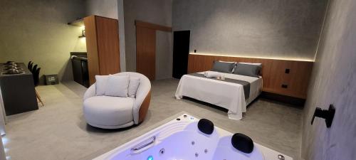 a room with a bed and a chair and a tub at Refúgio da Mata in Morretes