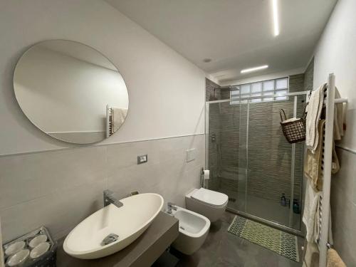 een badkamer met een wastafel, een toilet en een spiegel bij Appartamento in centro storico. in Camaiore