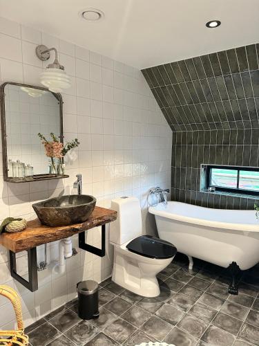 a bathroom with a sink and a tub and a toilet at Boutiquehotell Dahlbogården in Alingsås