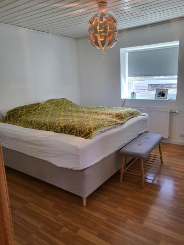 1 dormitorio con cama, ventana y lámpara de araña en Hyggelig lejlighed i Sandavágur, en Sandavágur